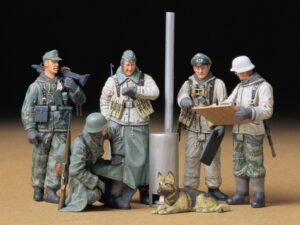 ★ This set depicts German soldiers from the middle stages of WWII in a variety of poses wearing winter uniforms and overcoats standing around a stove discussing battle strategies. ★It includes five figures depicting an officer and a noncommissioned officer looking over an open map, a soldier looking at his watch, another carrying a MG42 machine gun on his shoulder, and a squatting soldier. ★Also included in the set is a German shepherd figure lying down and accessories such as a newspaper and magazine. ★This set would go great in combination with winter-themed dioramas.